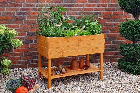 kleines bepflanztes Hochbeet vor Backsteinmauer